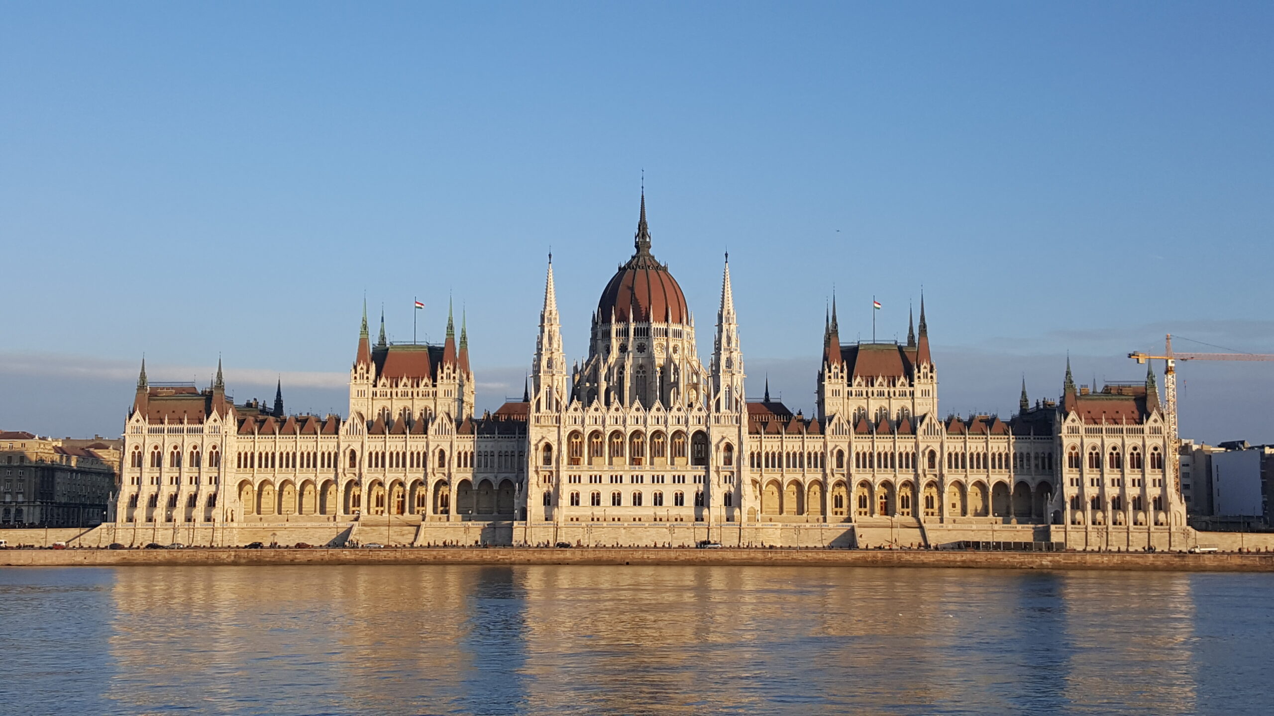 Majestatyczny parlament węgierski w Budapeszcie nad brzegiem Dunaju w złotym świetle słonecznym z charakterystyczną czerwoną kopułą